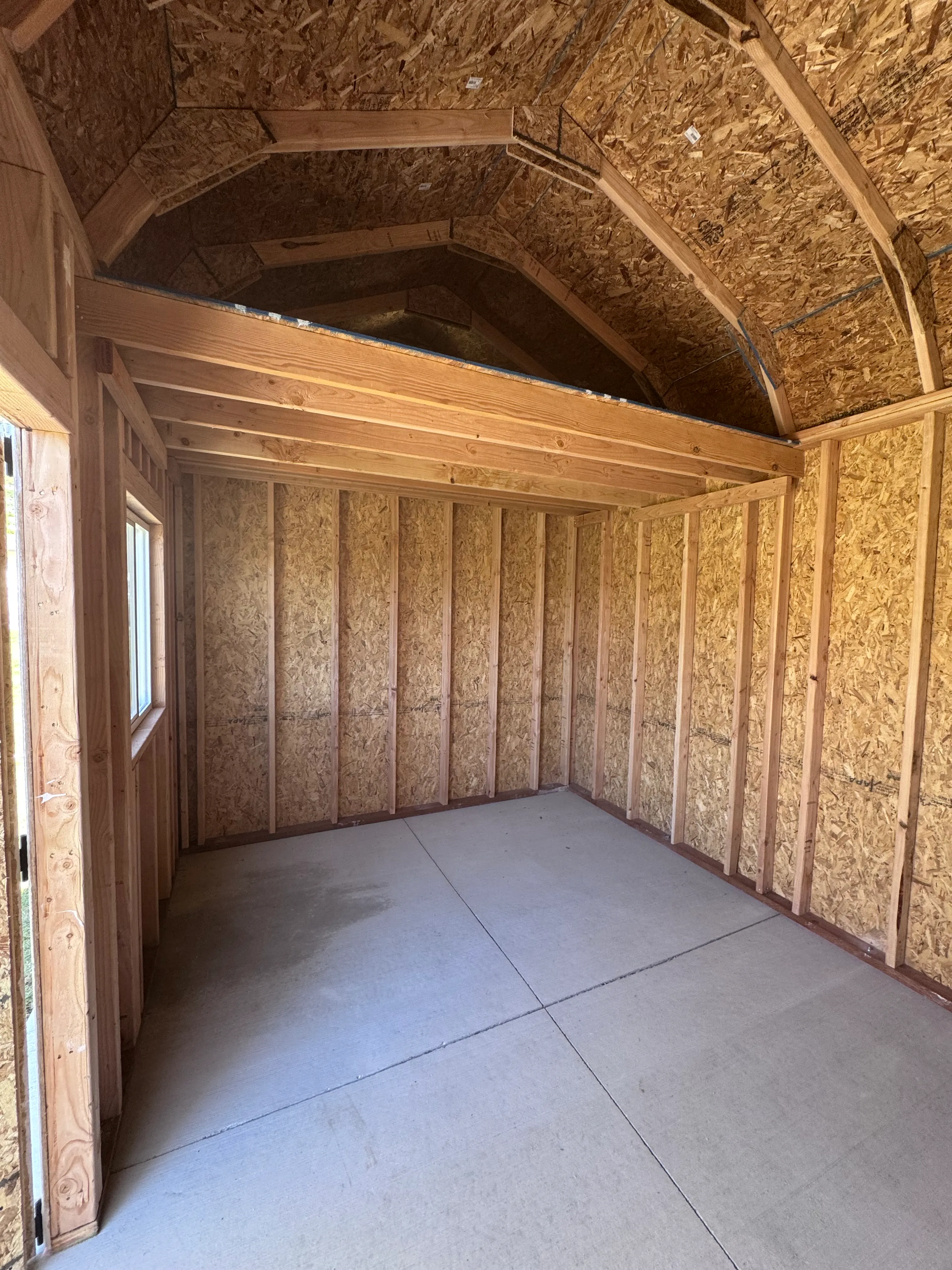 Interior of barn style shed showing gambrel roof framing and loft by ShedPro LLC